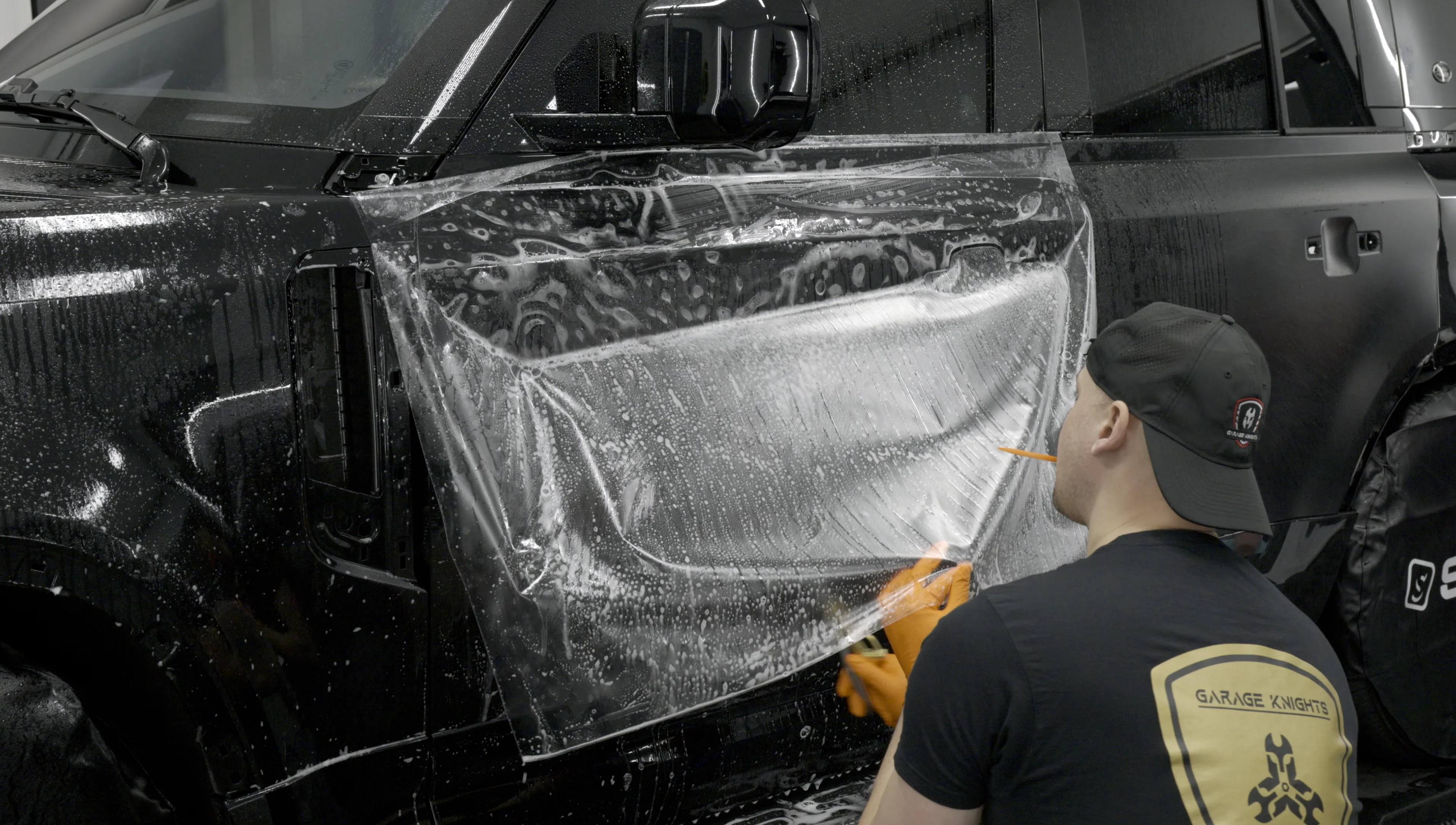 Kamil Matynia installing matte stealth paint protection film on a vehicle door panel at Garage Knights Ottawa
