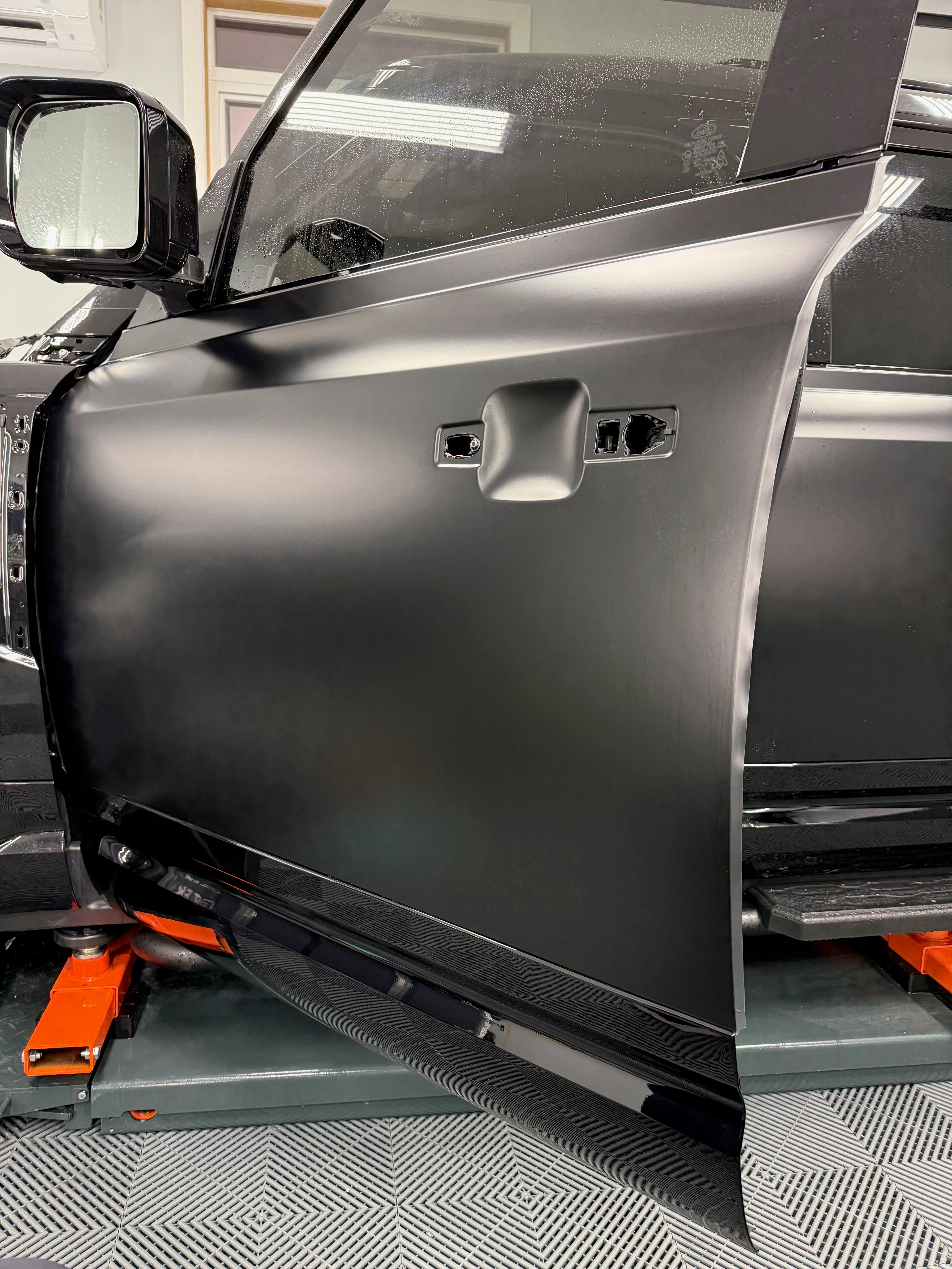 Door panel with handle removed showing full PPF edge wrap coverage — film extends behind all panel edges for a seamless, invisible finish