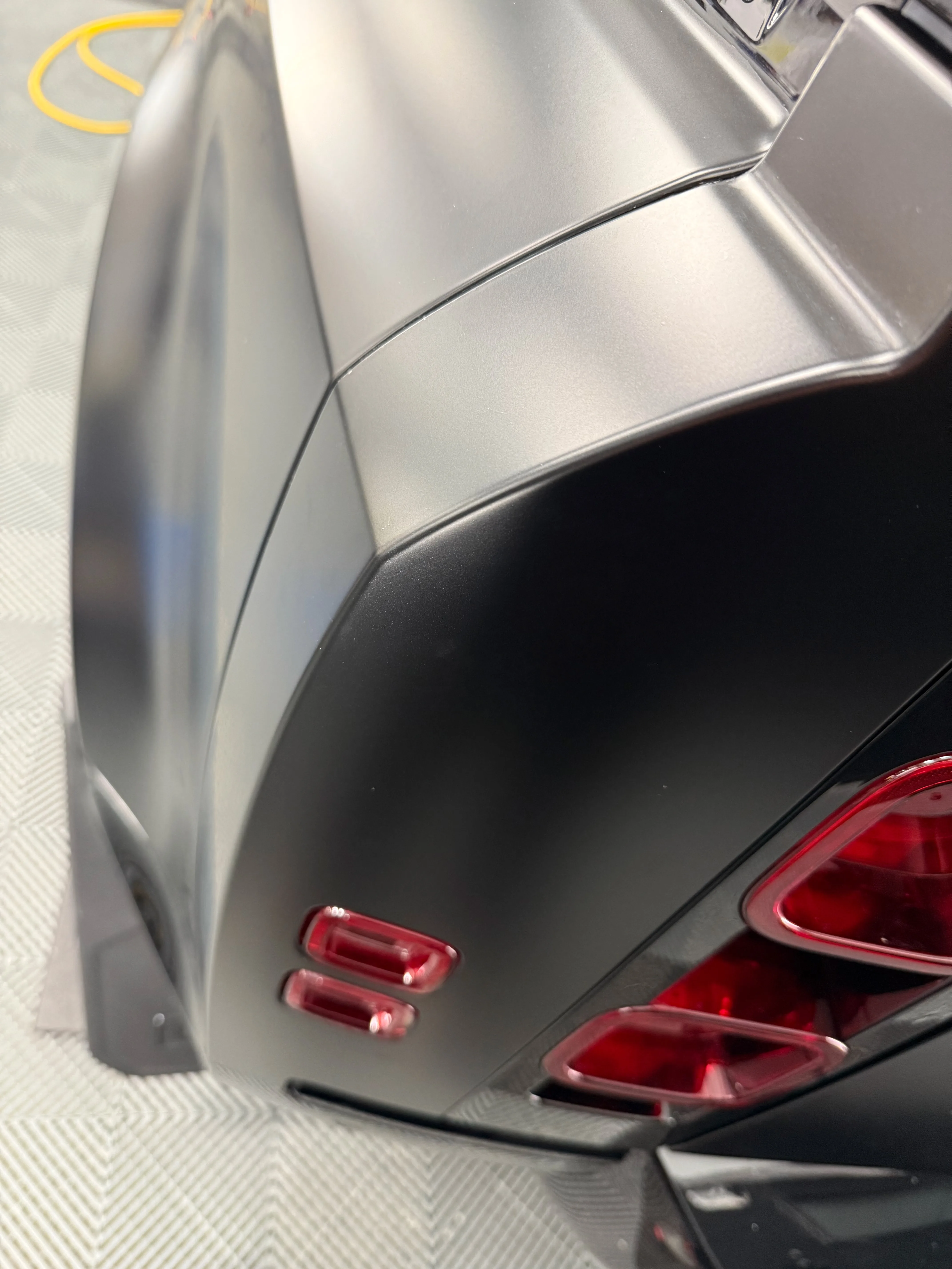 Close-up of rear quarter panel showing seamless PPF edge wrap around body line near tail light on a Land Rover Defender
