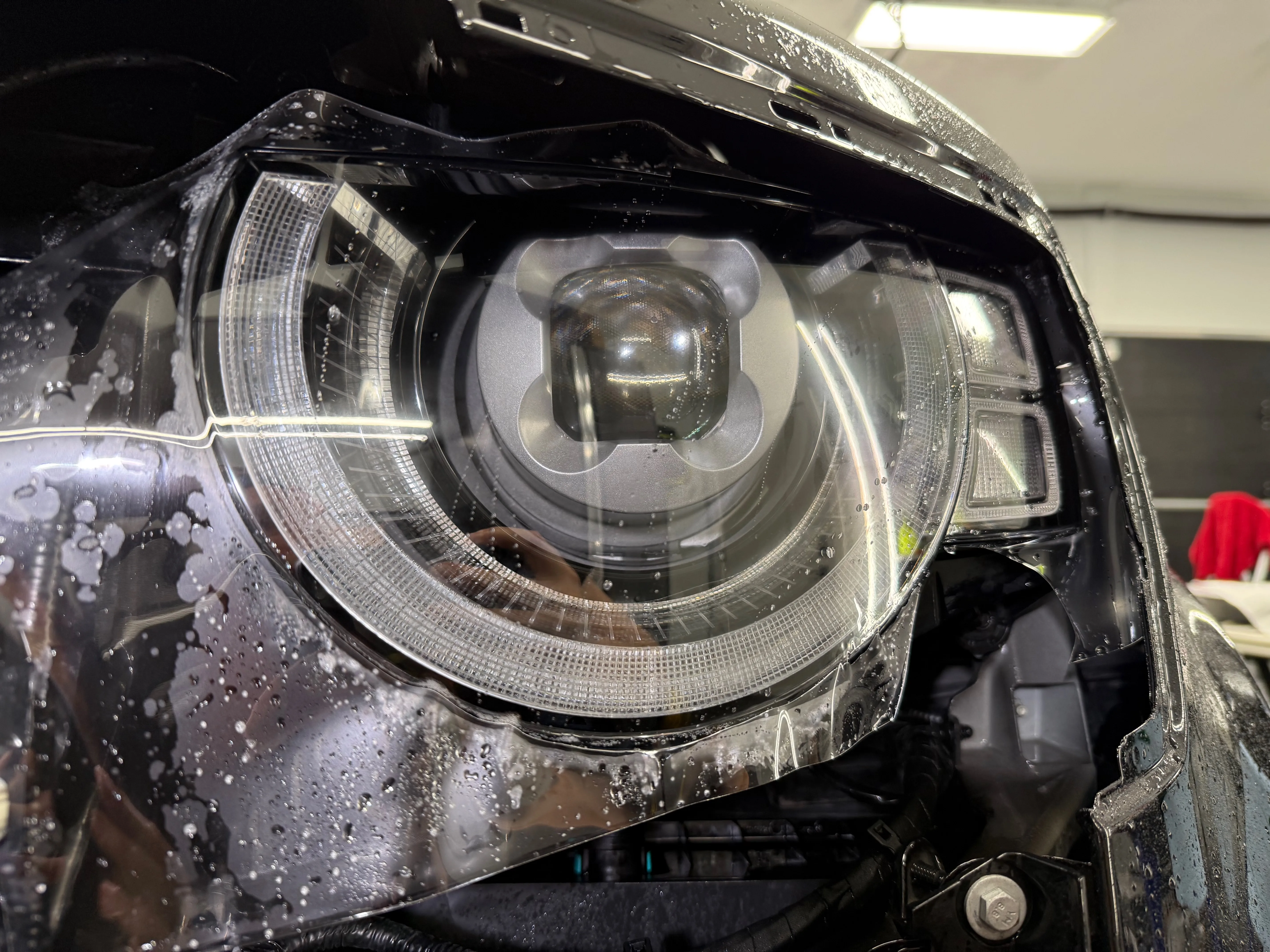 Headlight PPF installation in progress — slip solution applied during fitting