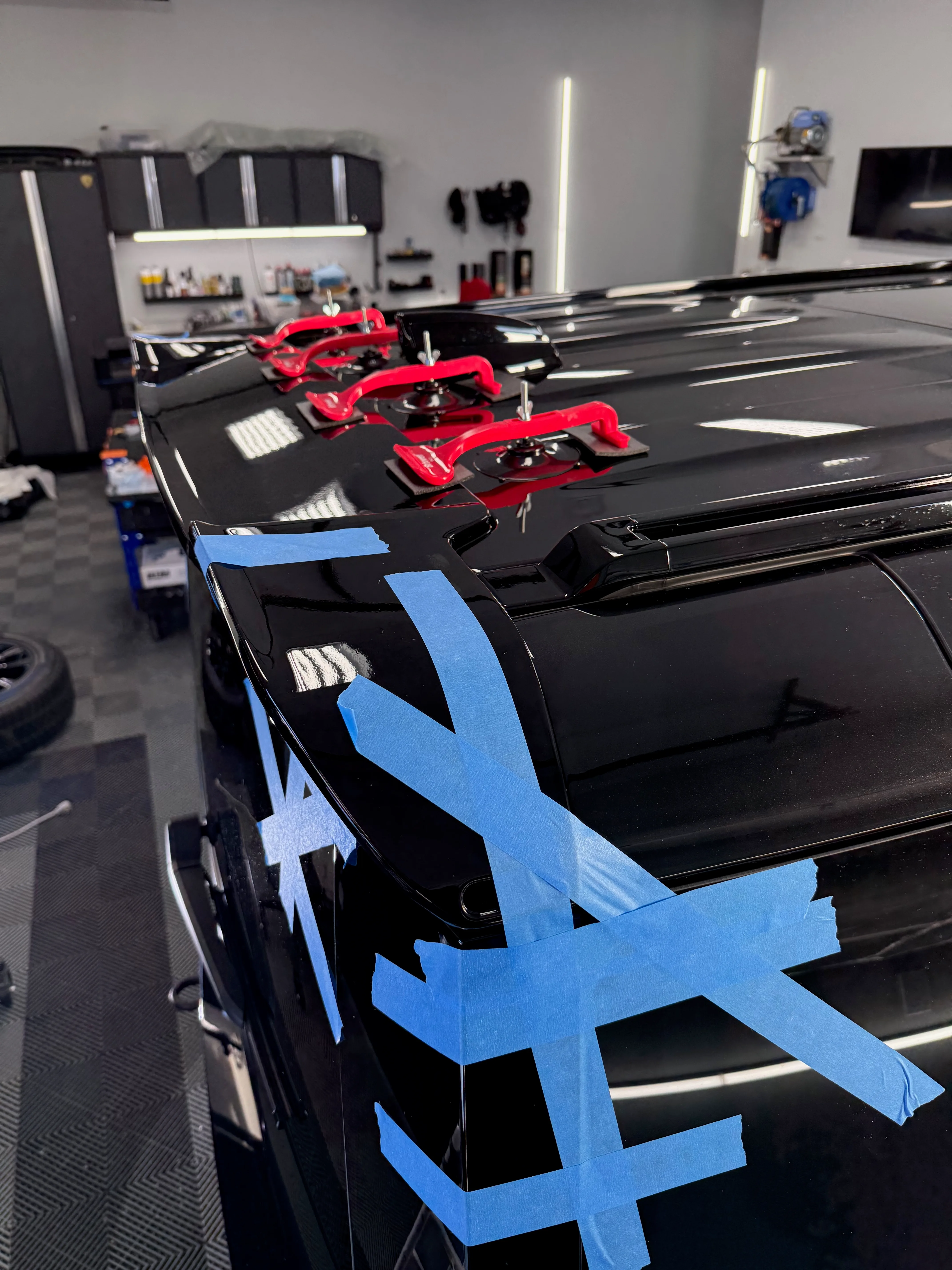 Urban Automotive roof spoiler being installed on Land Rover Defender — clamped and masked for precise bonding